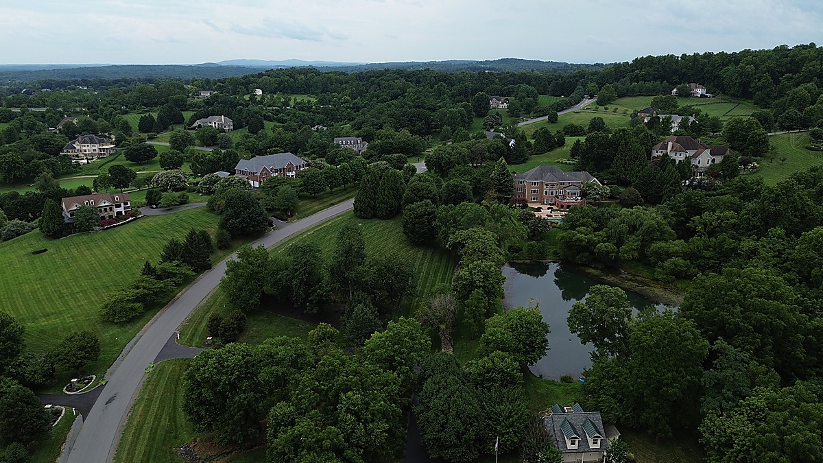 Aerial panoramic view of Loudoun County estates with pond and Blue Ridge Mountains