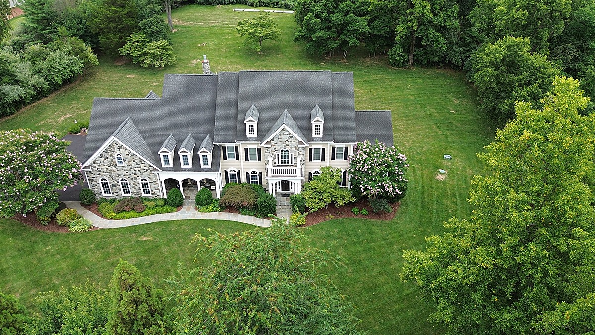 Aerial view of a Northern Virginia stone colonial surrounded by blooming crape myrtles